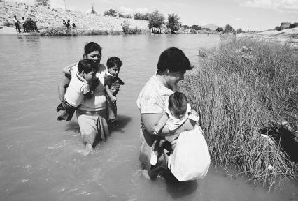 Mexican emigrants, with children in hand, cross the Rio Grande River. © Danny Lehman/Corbis.